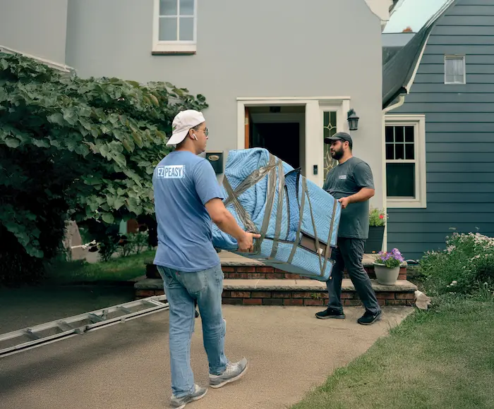 Two movers carrying a wrapped piece of furniture